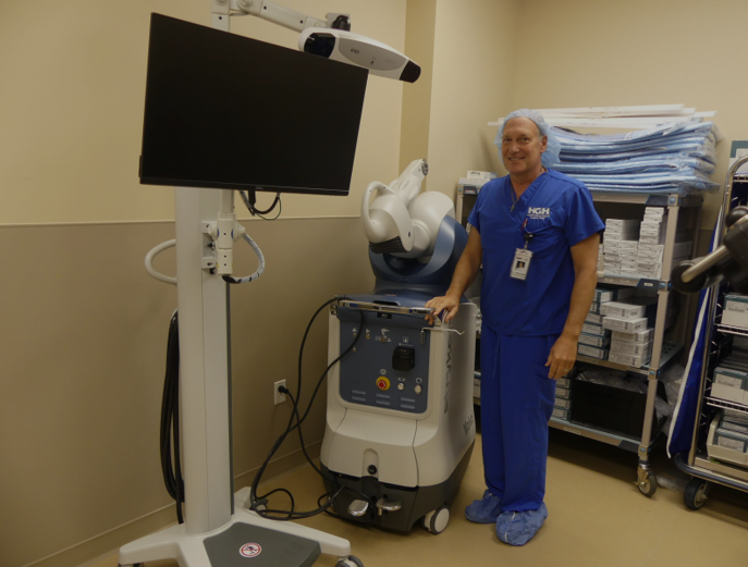 Dr. Meter posing with the robot, the CAT scan screen, and the cameras. 